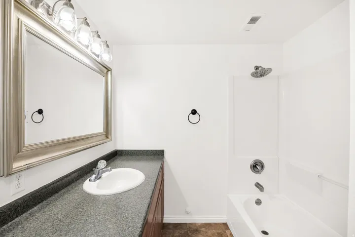 Built-in vanity with a dark-toned countertop, oval undermount sink, and a framed mirror