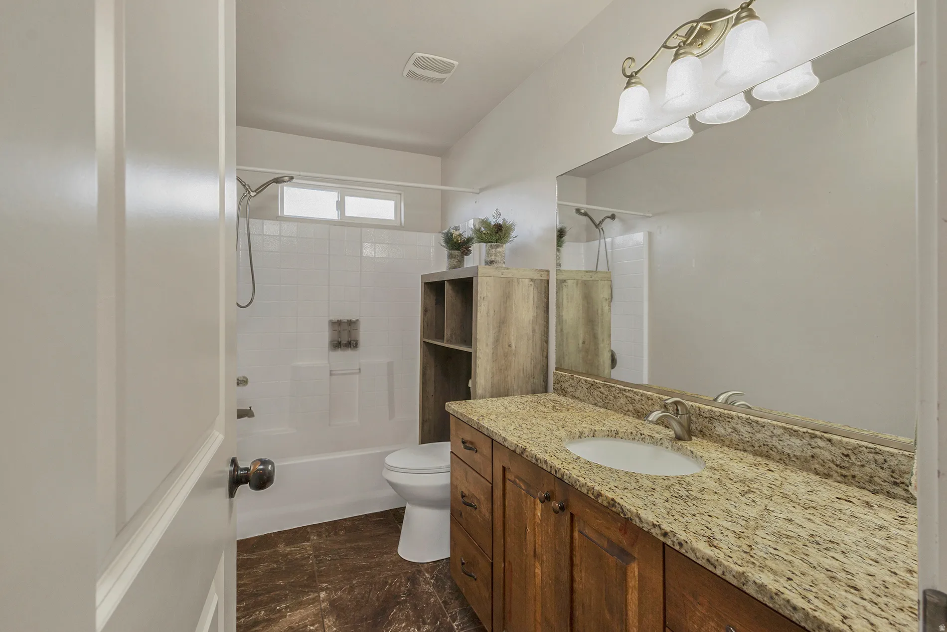 Bathroom featuring a vanity with a light-toned countertop, wood-finish cabinetry, and a large wall-mounted mirror