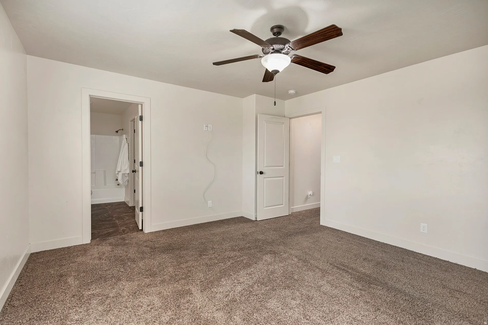 Plush carpeting, ceiling fan with light fixture, white walls, and white trim