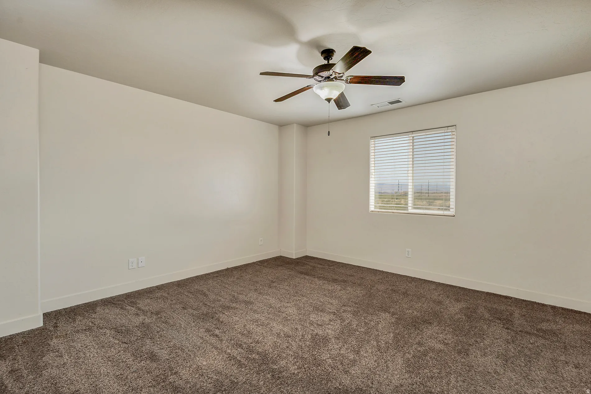 Recessed window with blinds, ceiling fan with integrated lighting, and neutral carpet flooring