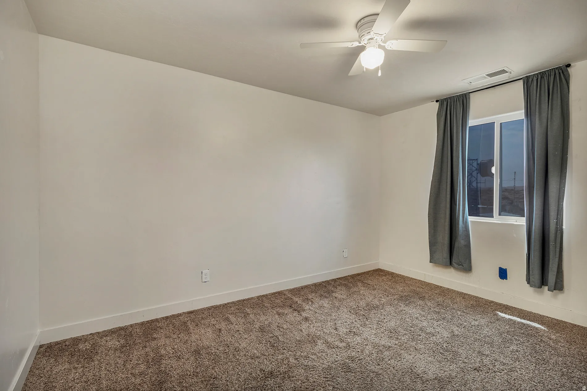 Carpeted room featuring a ceiling fan with integrated lighting and a double-pane window