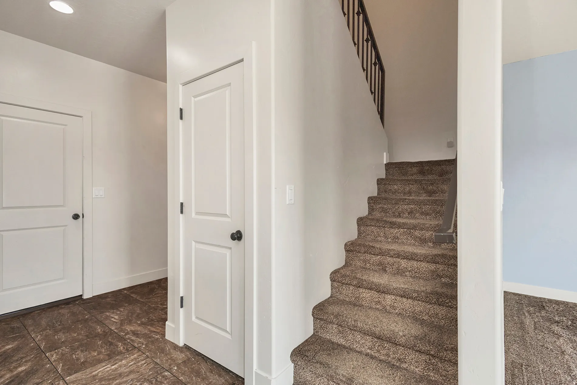Interior staircase with dark metal balusters and carpeted treads