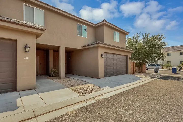 Two-story stucco exterior featuring a two-car garage with an overhead door, and a covered entry