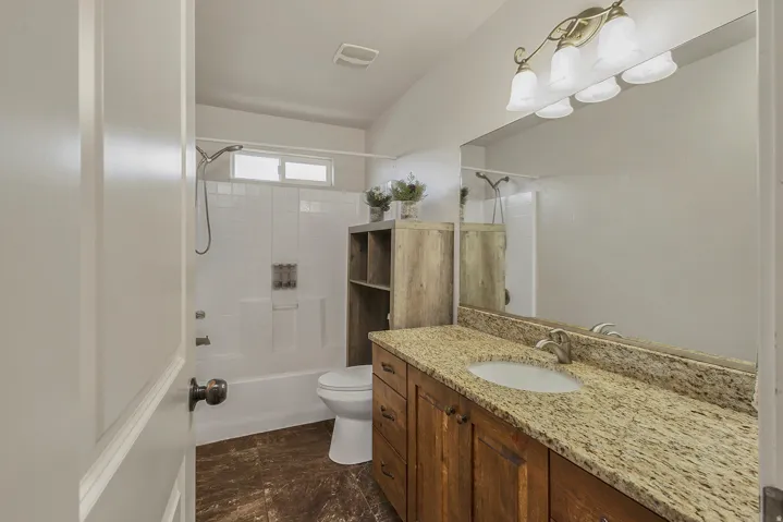 Bathroom featuring a vanity with a light-toned countertop, wood-finish cabinetry, and a large wall-mounted mirror