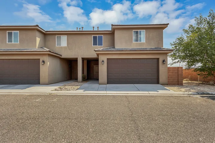Stucco exterior with panel garage door, covered entry, and paved driveway