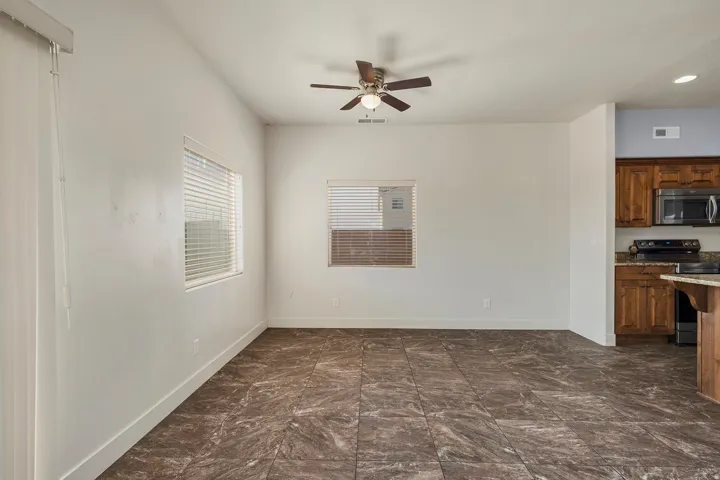 Spacious living area featuring large format tile flooring, a ceiling fan, and multiple windows