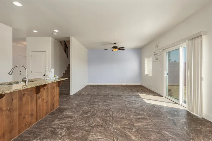 Granite-finish breakfast bar, stainless steel gooseneck faucet, recessed lighting, ceiling fan, and sliding glass door to outdoor space