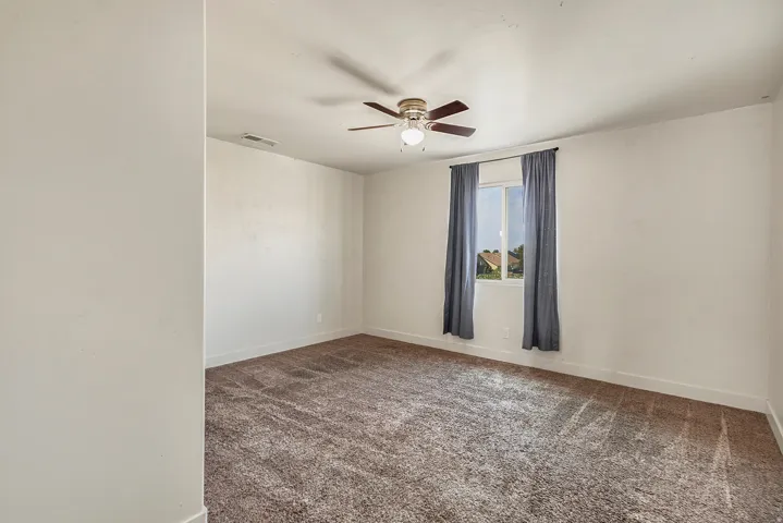 Recessed window with exterior views, ceiling fan with integrated lighting, and neutral tone carpeting