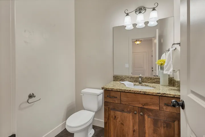 Wood-finish vanity with a stone countertop, undermount sink, and wall-mounted mirror