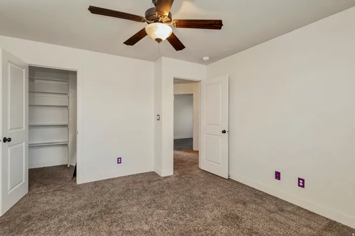 Recessed built-in shelving, ceiling fan with integrated lighting, and carpeted flooring