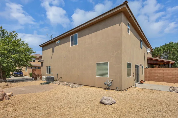 Stucco exterior with multiple windows, an air conditioning unit, and a covered patio area