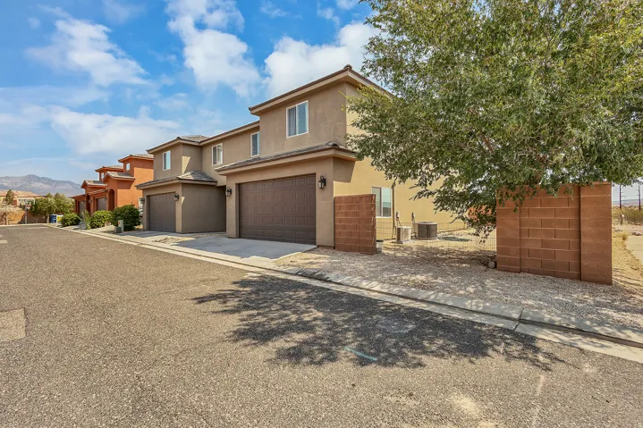Stucco exterior with multi-pane windows, two-car garage doors, and a tiled roofline