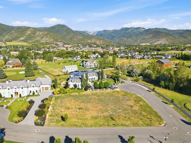 Expansive lot featuring a paved road, mountain backdrop, and surrounding mature trees