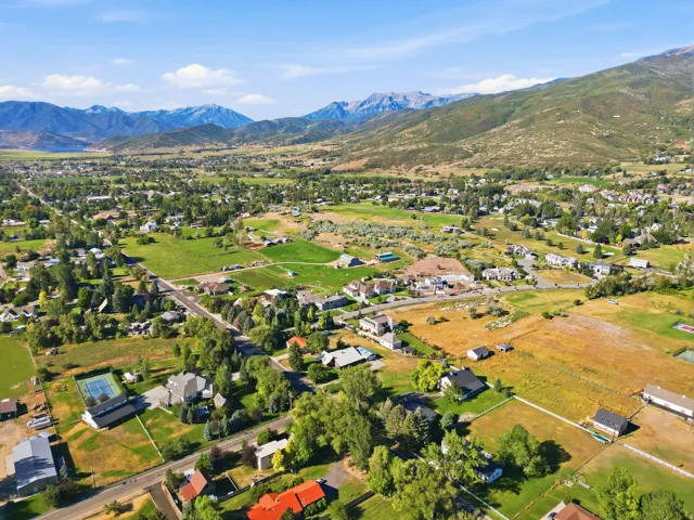 Expansive rural landscape with scattered residential properties, mature trees, and mountainous terrain