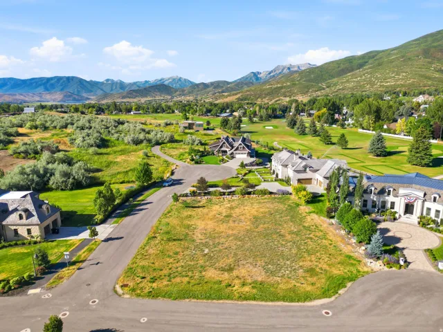 Expansive undeveloped lot with street access, surrounded by established residences, with distant mountain scenery