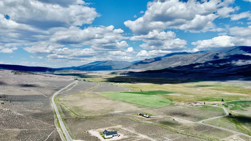 Expansive landscape featuring open fields, distant mountains, and a paved road