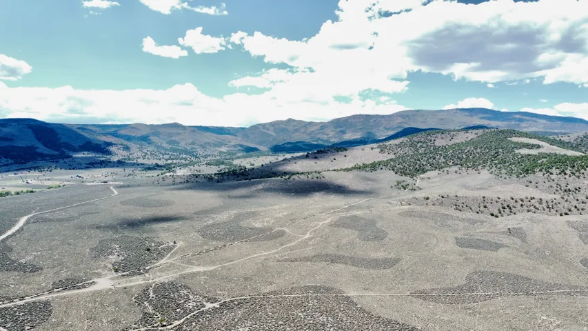 Expansive open land with undulating terrain and distant mountainous backdrop