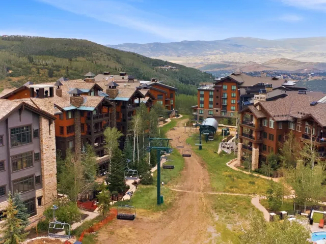 Mountain-side property featuring multi-story buildings with stone and wood-finish exteriors, multiple balconies, and visible chairlifts