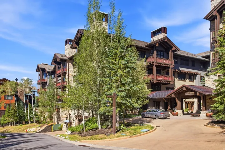 Multi-story building featuring stone and wood-finish siding, multiple balconies with wood railings, and prominent stone chimneys