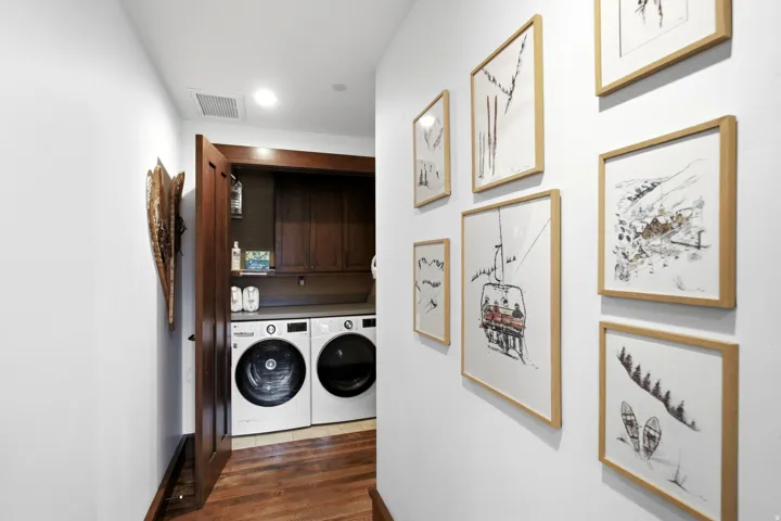 Laundry area with wood-finish flooring, dark wood cabinetry, and a light-toned countertop