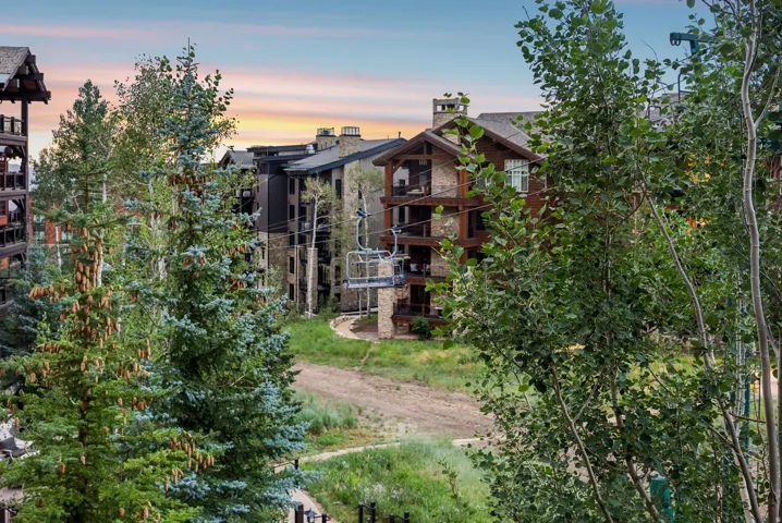 Building exterior with natural stone and wood siding, multiple private balconies, and a gabled roofline