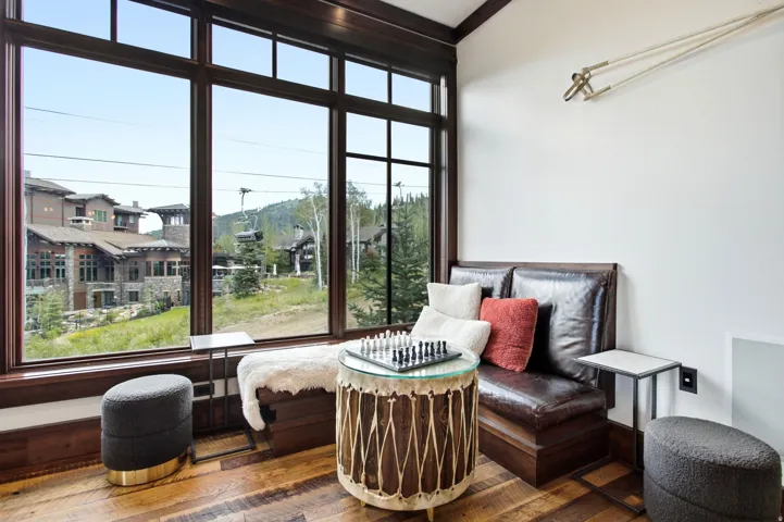 Expansive window wall with dark wood trim, built-in bench seating, wood-finish flooring, and a wall-mounted articulating light fixture