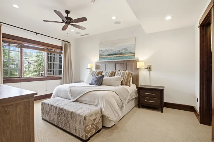 Wood-trimmed windows, recessed lighting, ceiling fan, carpeted flooring, and a wood headboard with integrated lighting