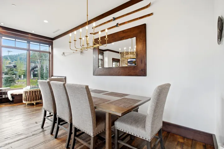 Wood-finish flooring, large picture windows, wood-framed mirror, exposed wood beam, and a multi-arm chandelier