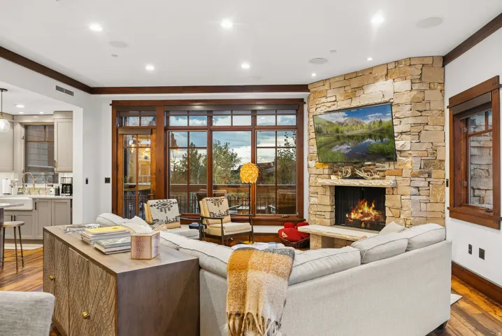 Stone-clad fireplace with a hearth, expansive wood-framed windows, recessed lighting, and wood-finish flooring
