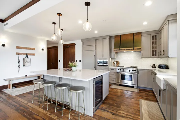 Gourmet kitchen with stainless steel appliances, custom range hood, shaker-style cabinetry, and a large center island with built-in beverage cooler