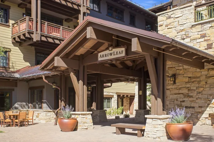 Covered entry with exposed wood beams, stone accents, and a slatted wood ceiling