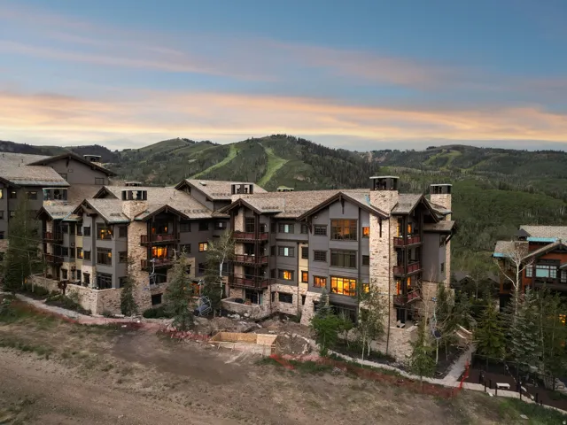 Multi-story dwelling featuring stone and wood siding, multiple balconies, and a pitched roofline