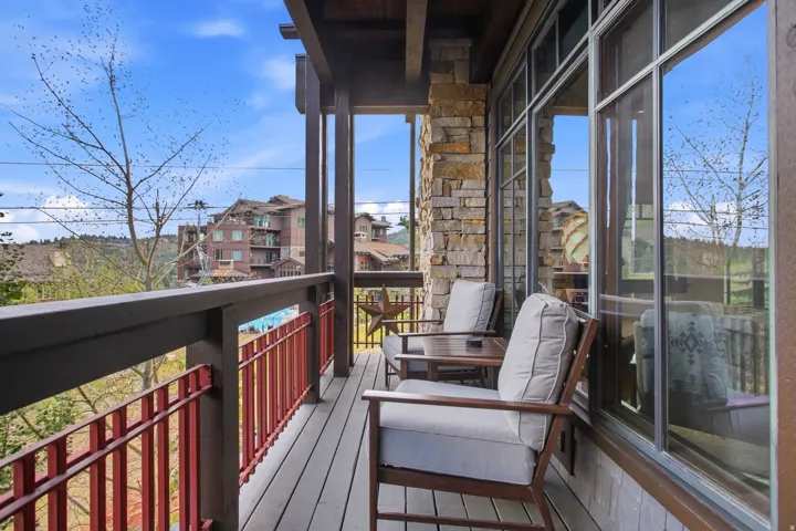 Private balcony featuring wood-finish decking, stone veneer accent wall, and large windows