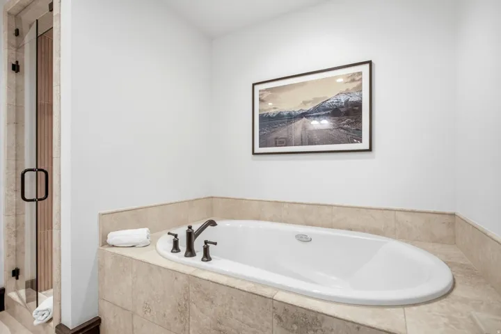 Built-in soaking tub with dark bronze fixtures and a tile surround