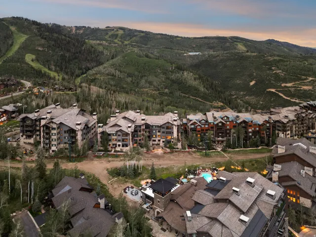 Community featuring multiple multi-story buildings with pitched roofs, surrounded by extensive natural landscaping