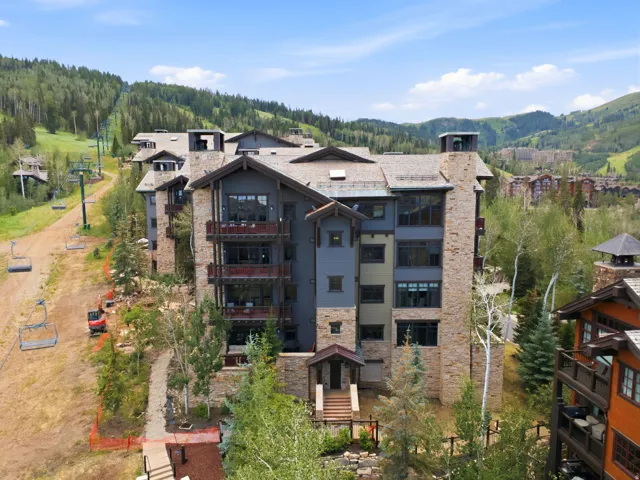 Multi-story property featuring stone and siding exterior, multiple private balconies, and a sloped shingle roof