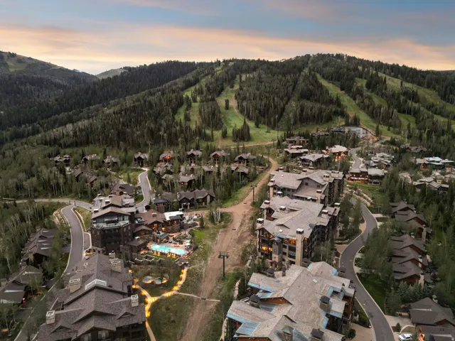 Mountainous terrain with natural tree coverage and a collection of multi-story buildings and single-family residences