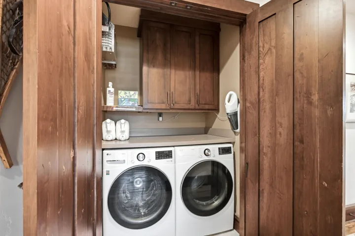 Built-in laundry closet with a front-loading washer and dryer, solid surface countertop, and wood cabinetry
