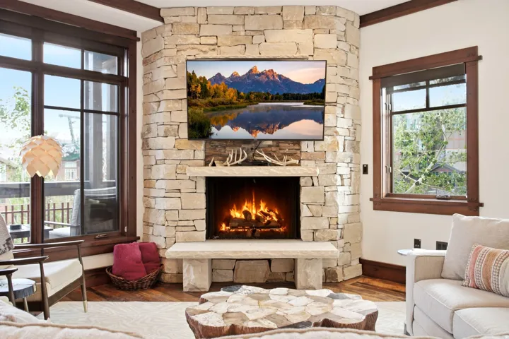 Corner fireplace with a stone surround, stone hearth, and integrated mantel