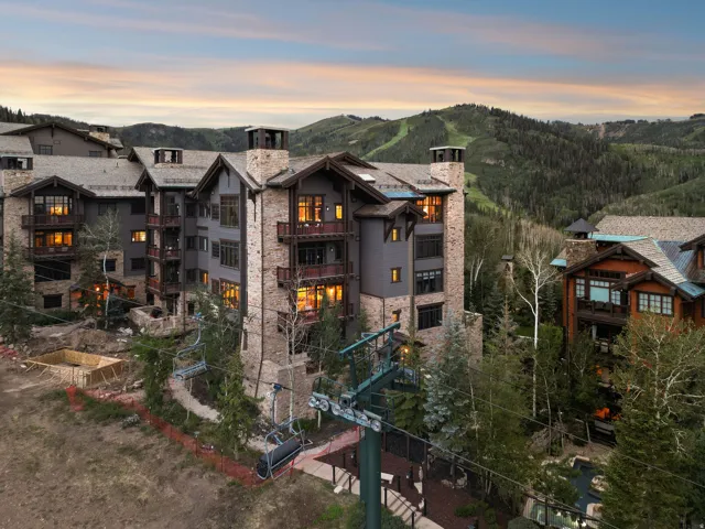 Multi-story property featuring stone and wood siding, multiple balconies, and a distinctive ski lift infrastructure