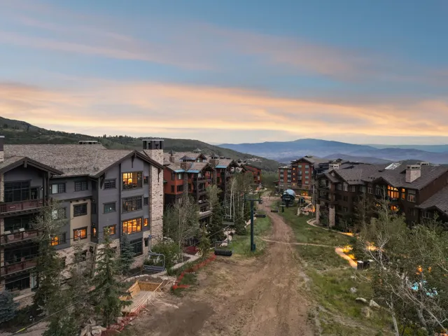 Multiple structures featuring stone and wood-finish exteriors, varied rooflines, and prominent mountain scenery