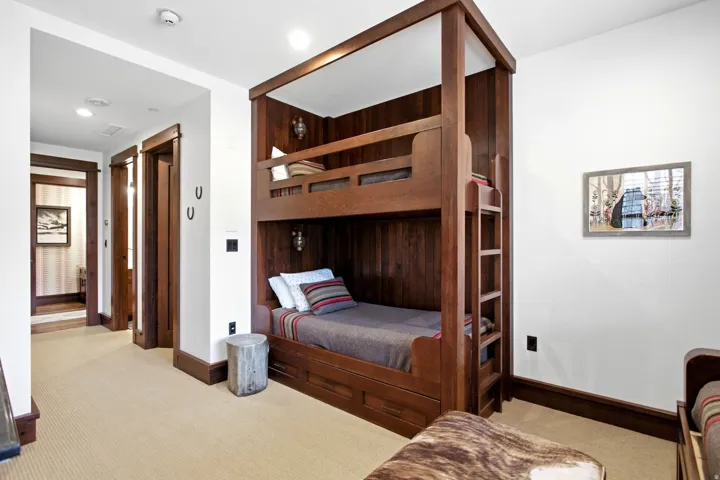 Built-in bunk bed structure with wood paneling, integrated ladder, and recessed lighting
