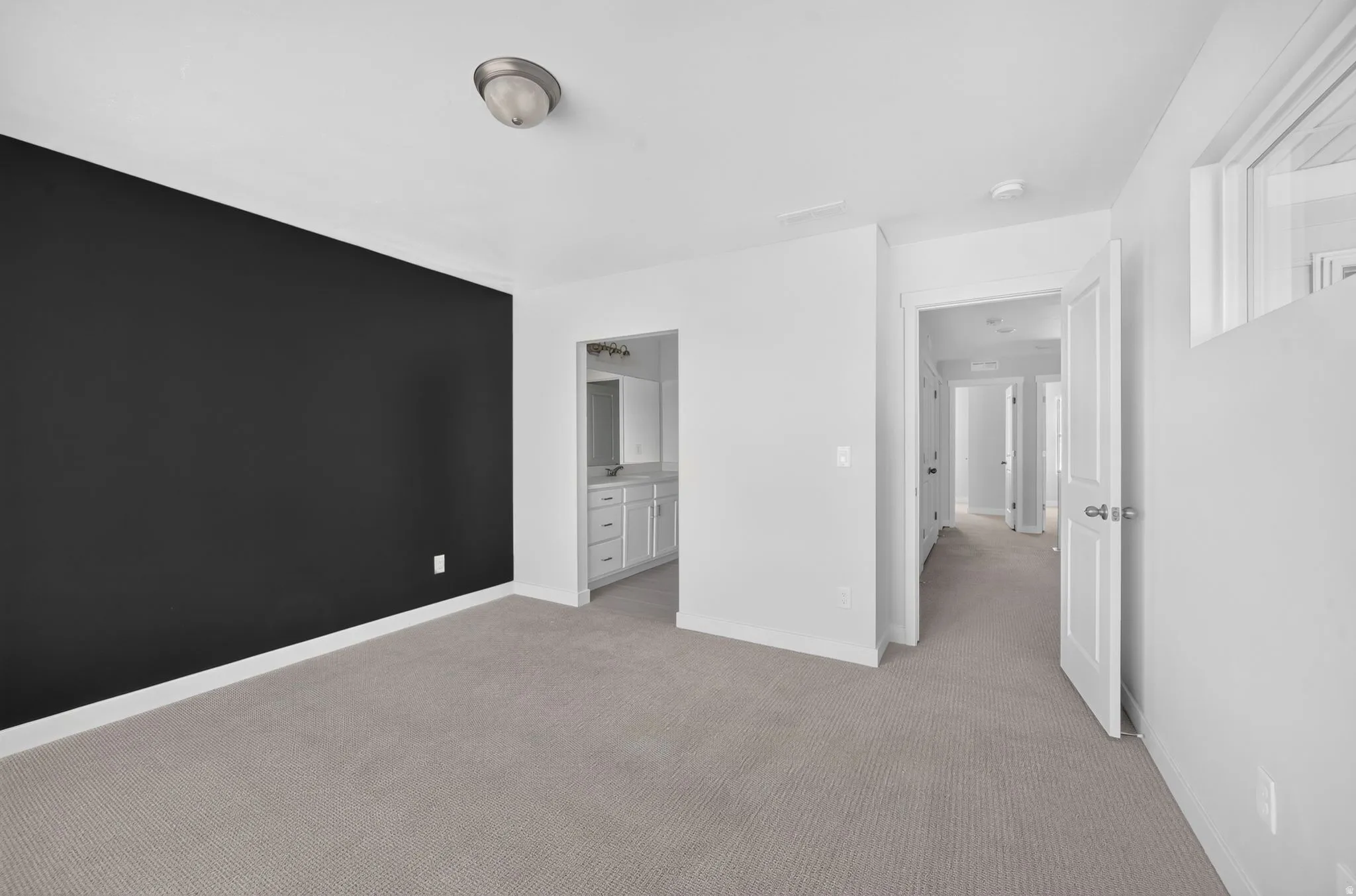 Plush carpeting, a distinctive accent wall, and a pass-through to a vanity space