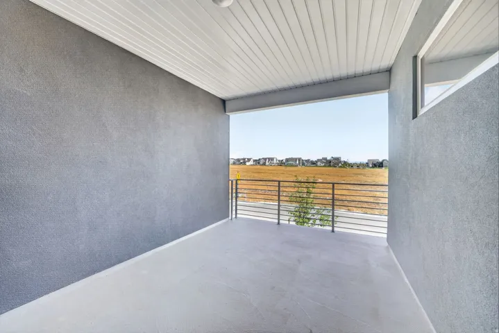 Covered balcony with a smooth concrete floor, gray stucco walls, and a white slatted ceiling