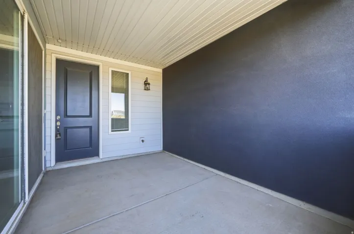 Covered concrete patio with a dark paneled entry door