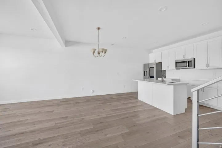Open-concept living space with wood-finish flooring, recessed lighting, and a vaulted ceiling with exposed beam