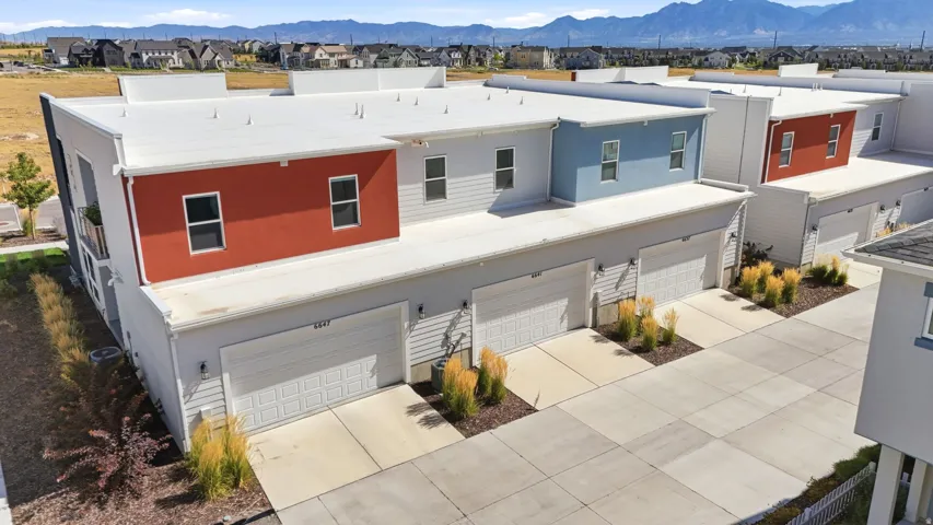 Contemporary townhome exteriors featuring multiple two-car garages, flat roofs, and varying facade colors