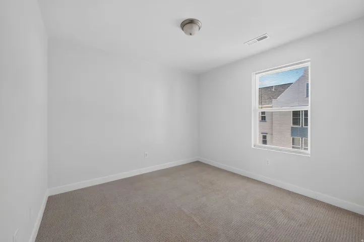 Neutral tone wall paint, flush mount ceiling light fixture, single window with blinds, and carpeted flooring
