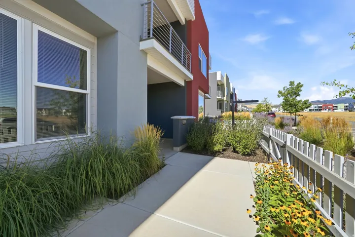 Modern exterior with red and gray facade, white window trim, contemporary balcony railing, and a concrete walkway