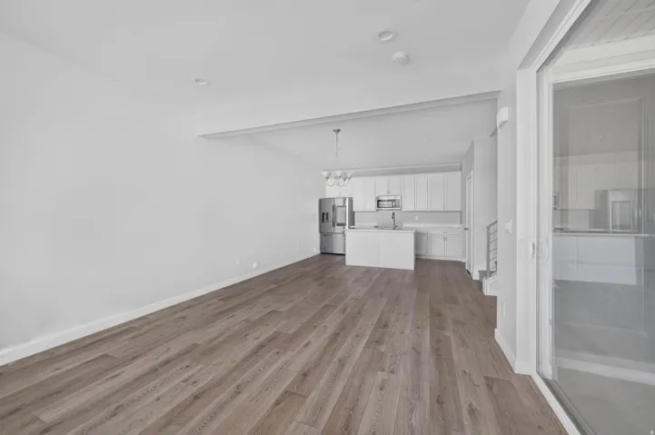 Open-concept living area with wood-finish flooring, recessed lighting, and a sliding glass door